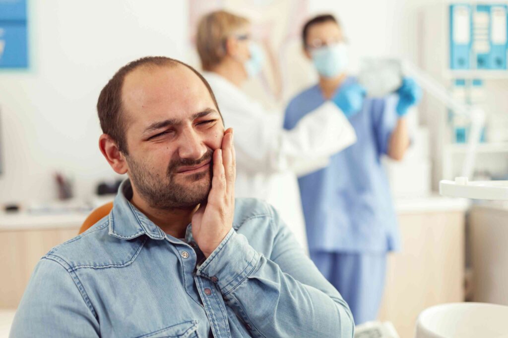 Patient holding jaw in dental pain.
