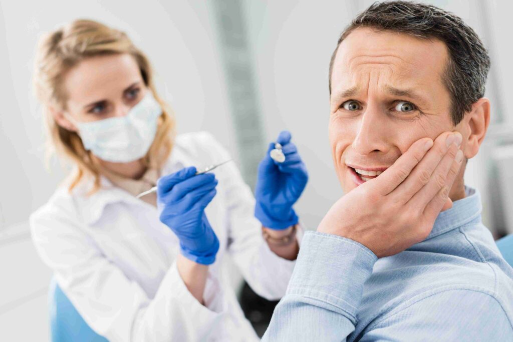 Patient holding cheek with tooth pain during a dental exam.