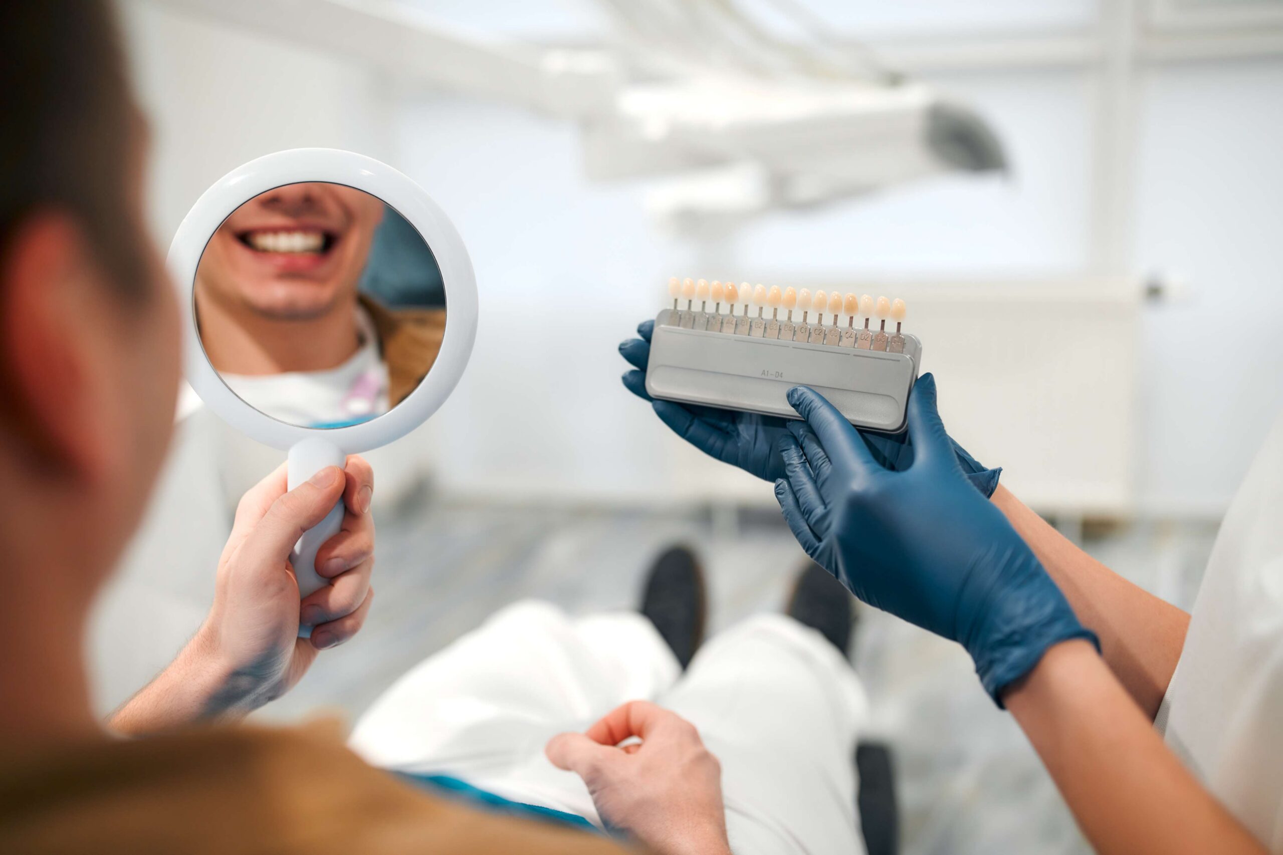 Patient comparing smile shades with a dentist.