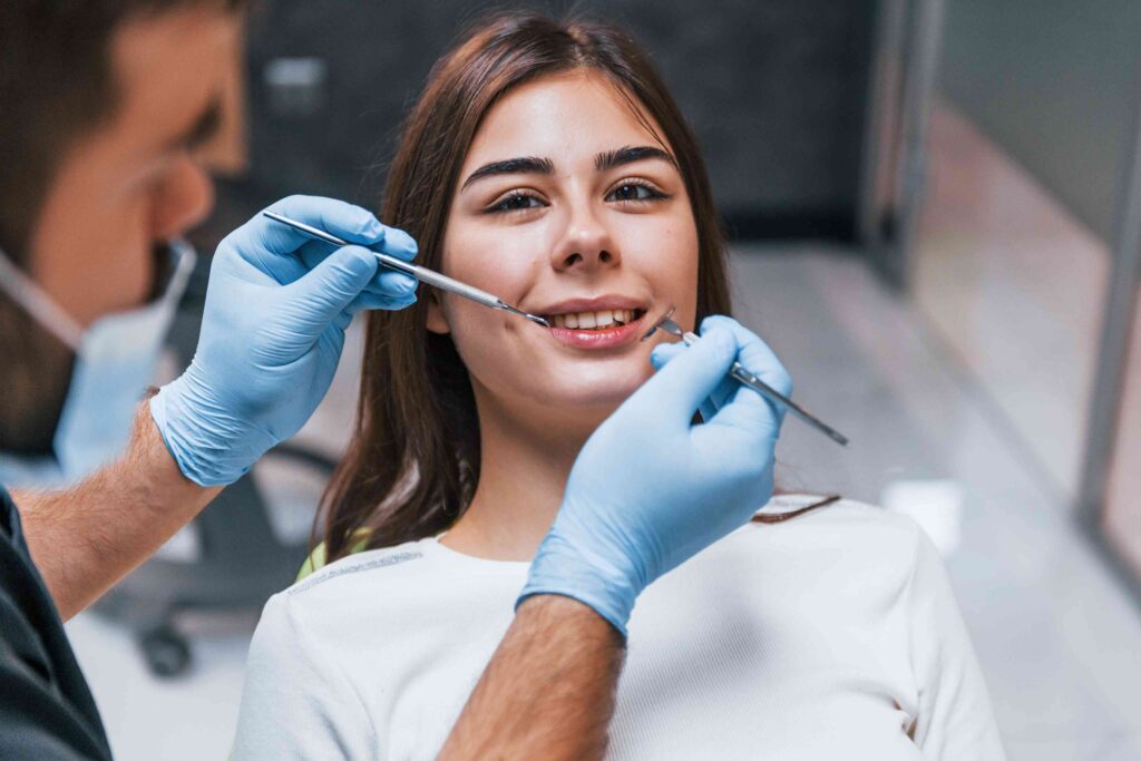 Dentist examining patient’s teeth with dental tools